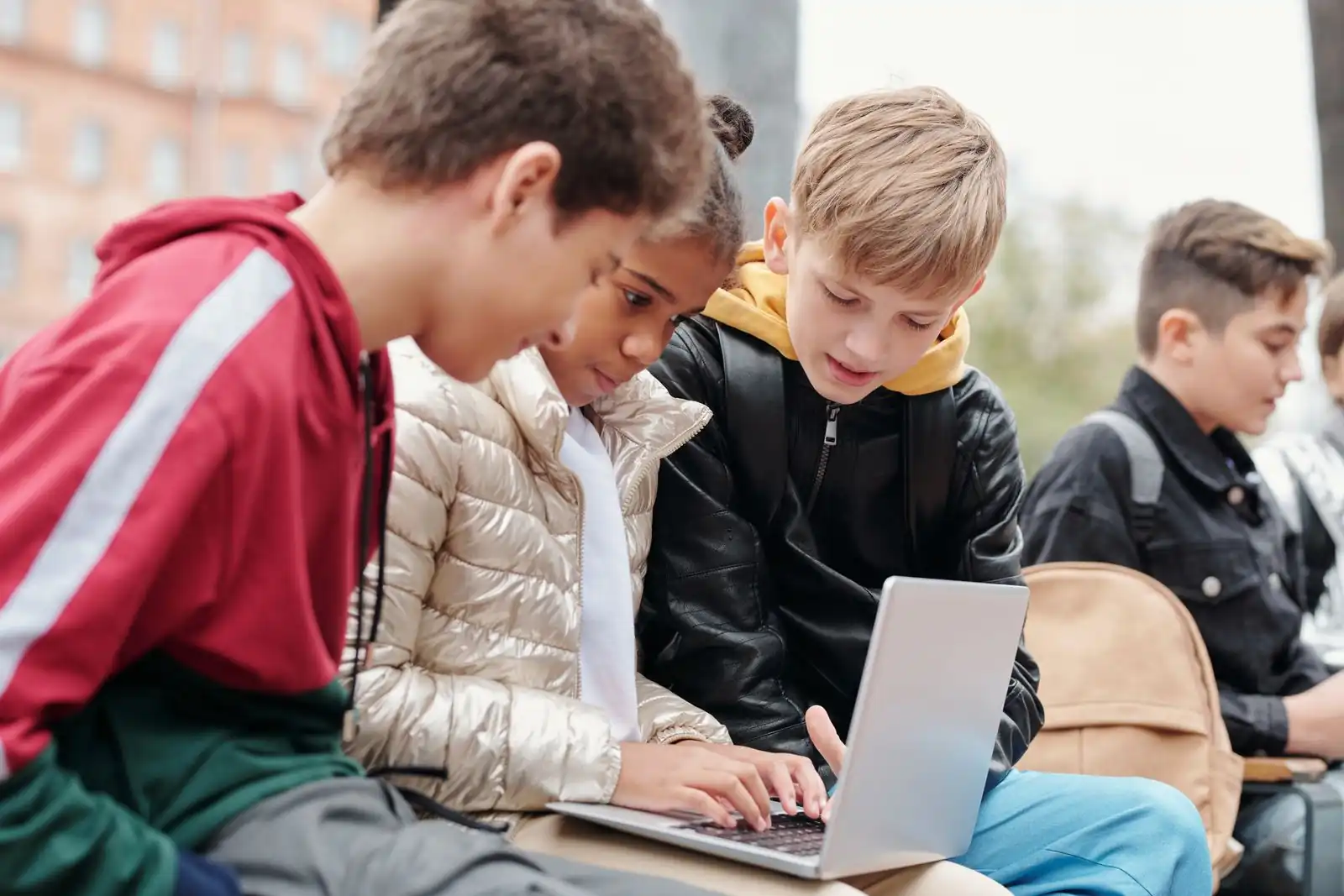 A small group of learners working together on a laptop